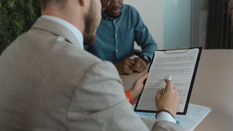 Recrutadora revisando documentos de candidato em entrevista profissional