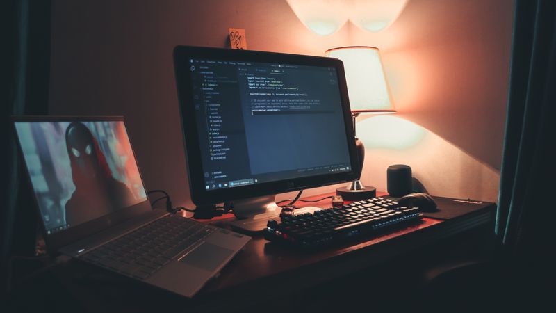 Workspace de programação com duas telas mostrando código em ambiente acolhedor